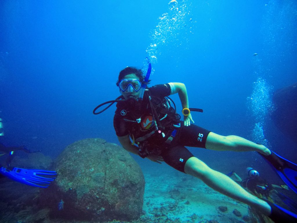 Scuba diver with rental gear in the ocean in Thailand, with hands on hips underwater.